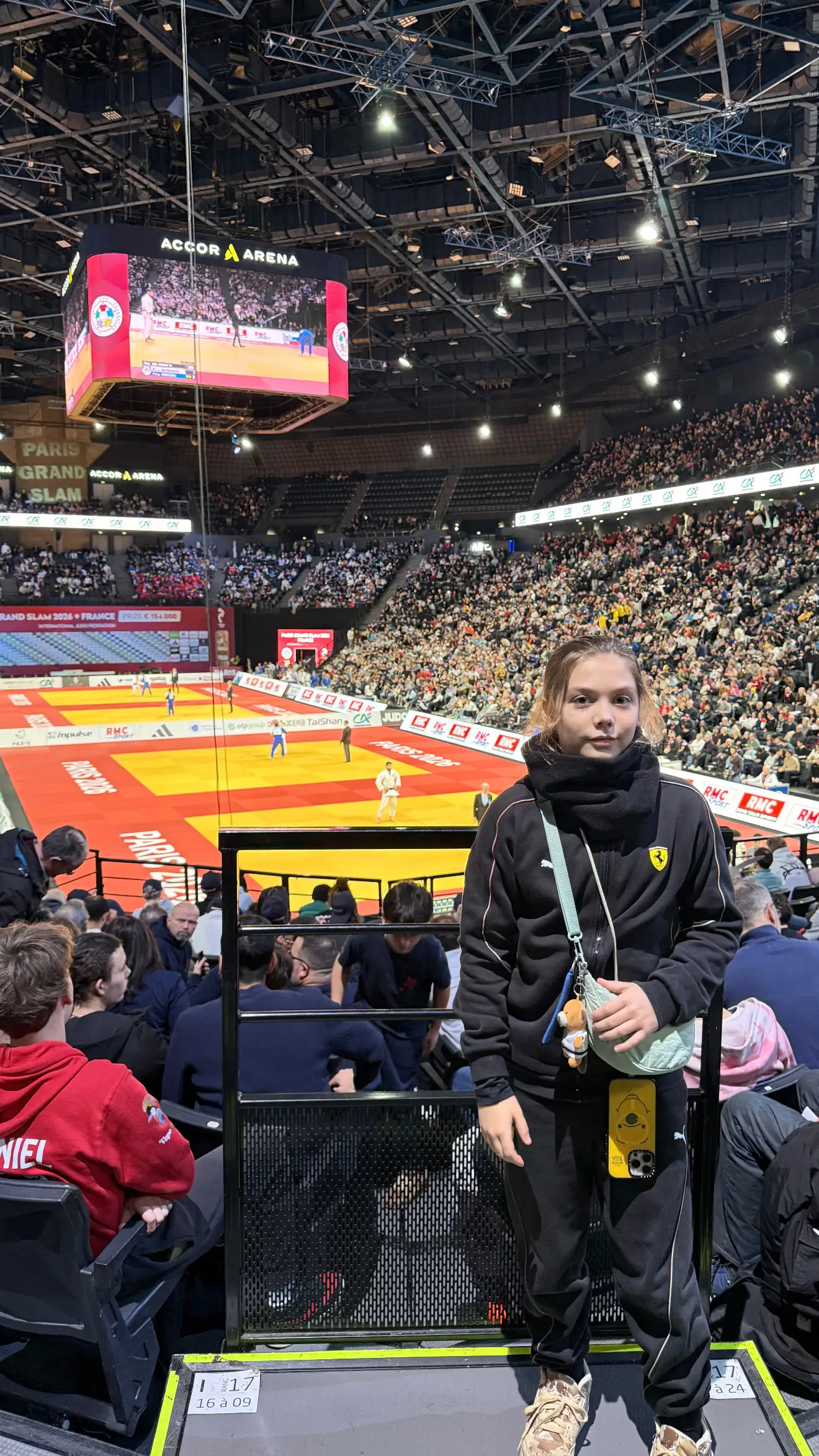 Melissa standing at the front of the stands in a competition hall at night