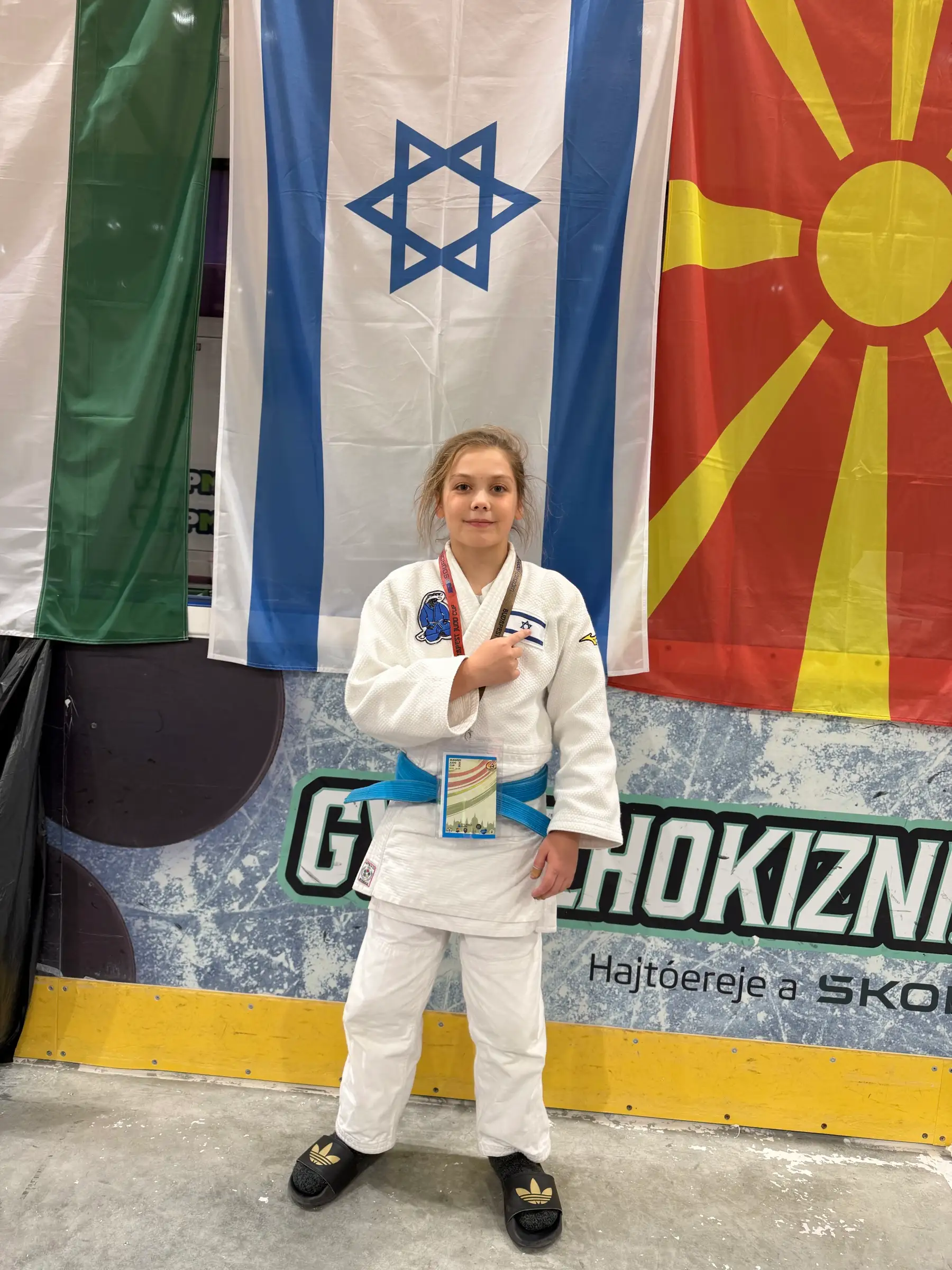 Melissa in a judo suit standing on the mat under the flags