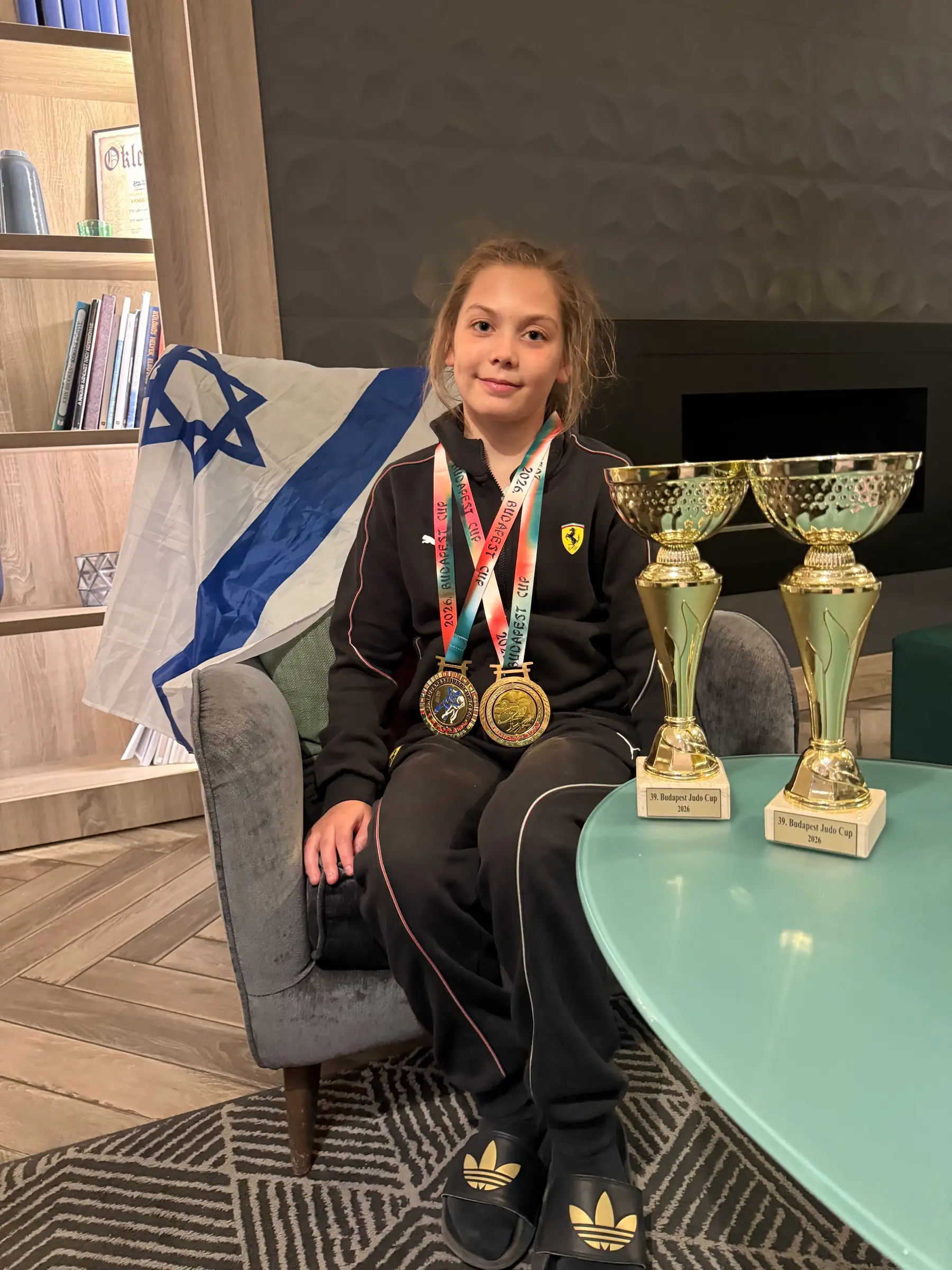 Melissa sitting in an armchair with medals, trophies and an Israeli flag