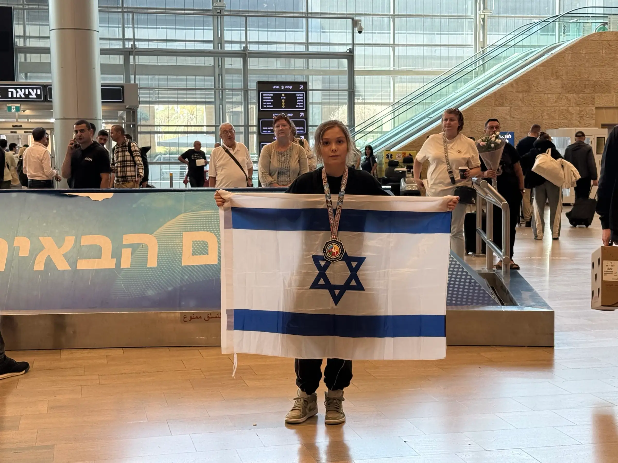 Melissa with a medal holding an Israeli flag at the airport