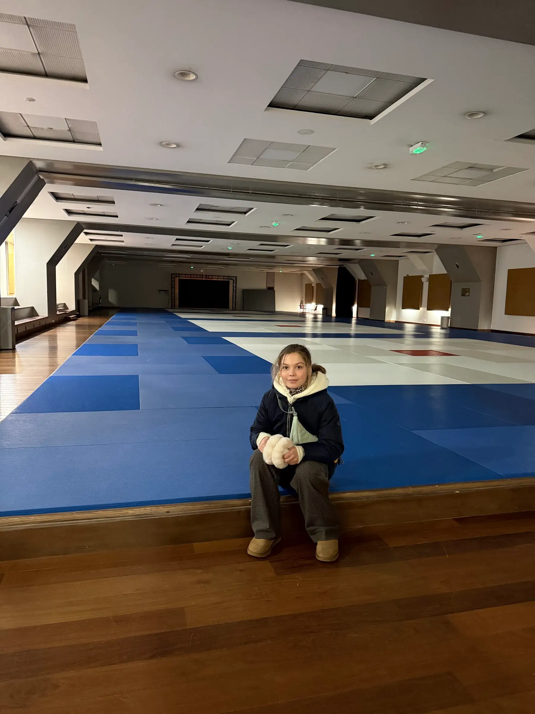 Little Melissa sitting in an empty training hall