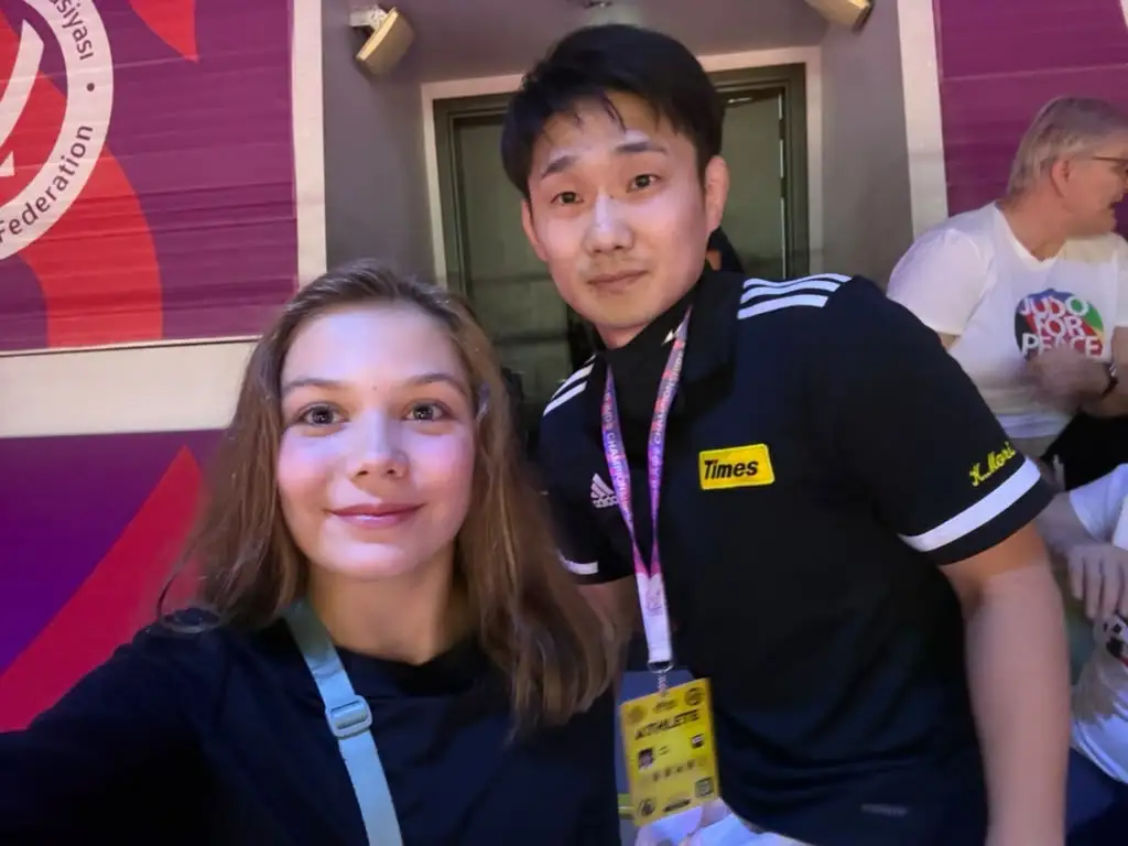 Melissa and a man wearing an organizer badge in a selfie in the hall
