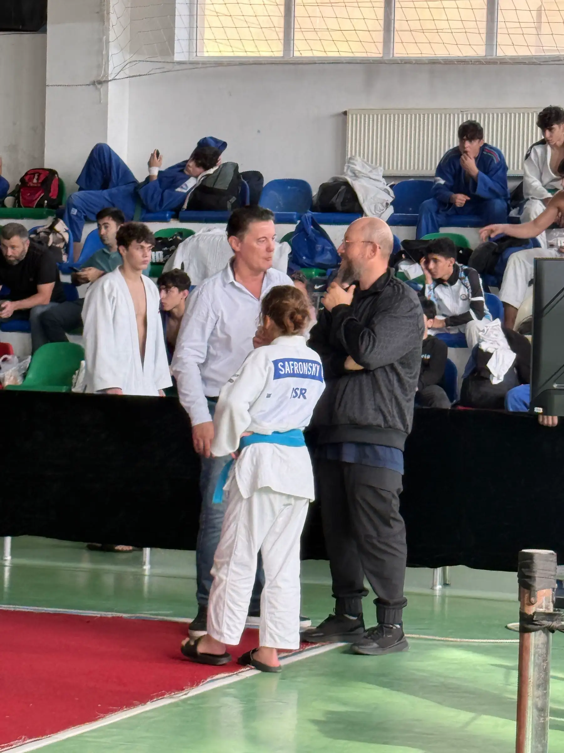 Melissa in a judo suit with SAFRONSKY on the back, among people in a competition hall