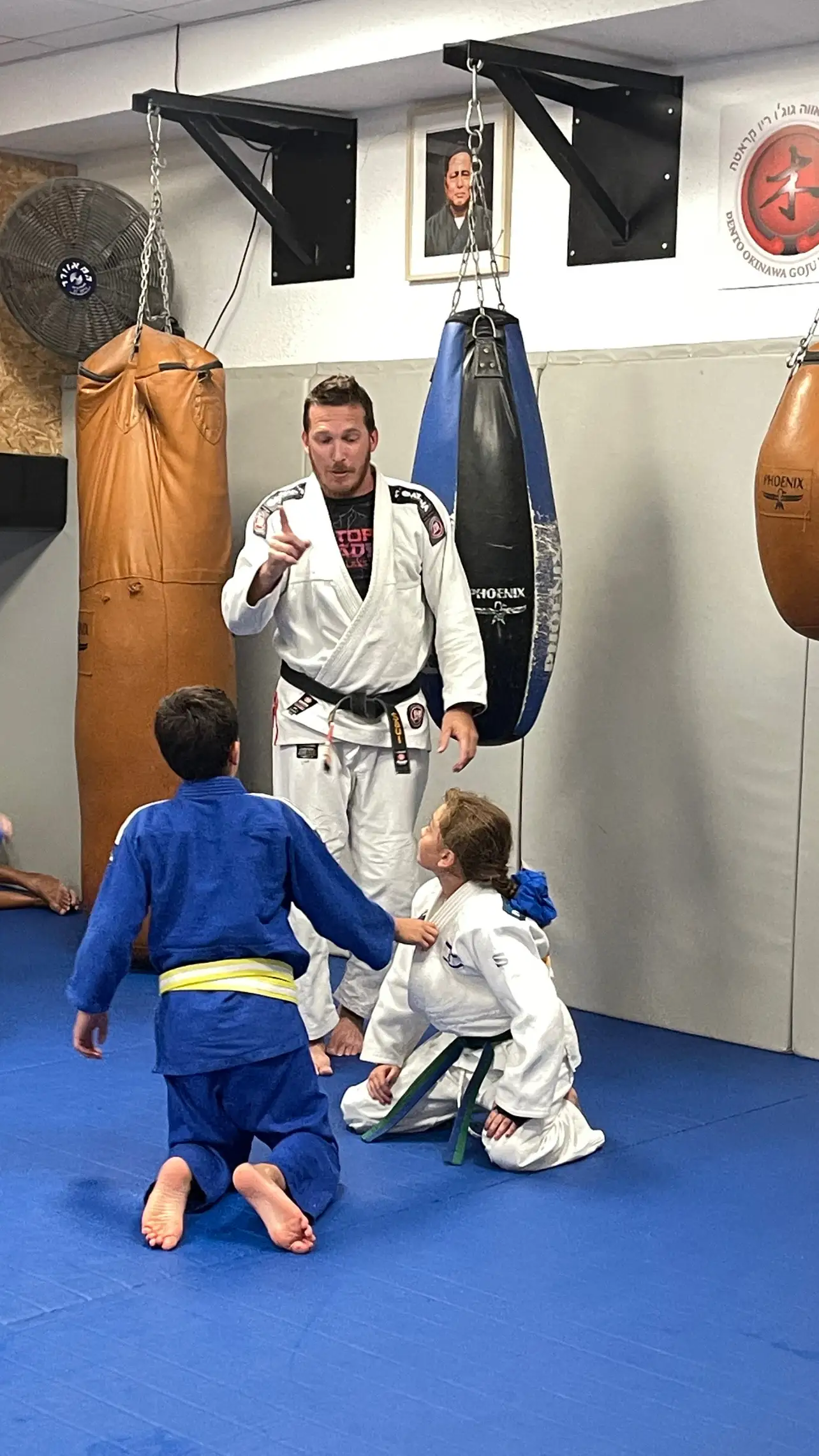 Children and a coach in a judo class on a blue mat